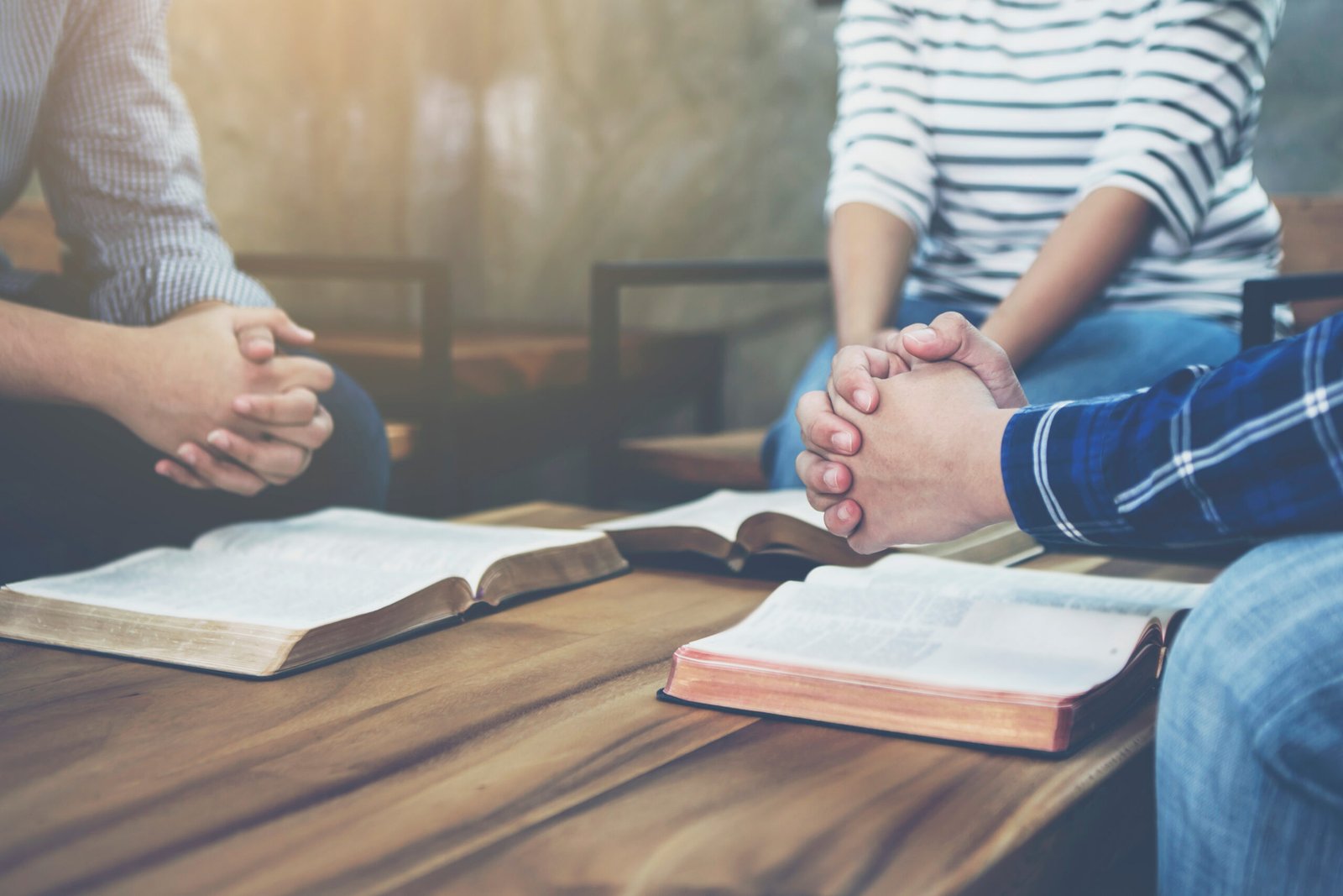 Two people praying together with open Bibles on the table